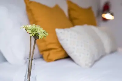 a vase with a flower on a bed with pillows at Papa 1T · Papa Studio Central Garden View in Porto