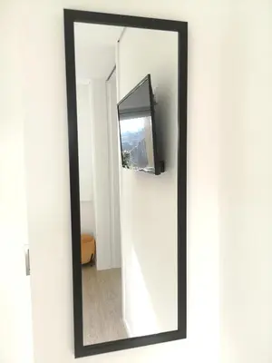 a mirror with a black frame hanging on a wall at OportoView Prestige Apartment in Porto