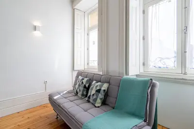 a couch in a living room with two windows at Host Wise - Homely Noble Flats - Garden & Jacuzzi in Porto