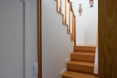 a stairway with wooden stairs and a white wall at Box Market Square Apartment in Porto