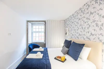 a hotel room with a bed with a blue bedspread at Elegant Downtown 1BR Flat w/ AC by LovelyStay in Porto