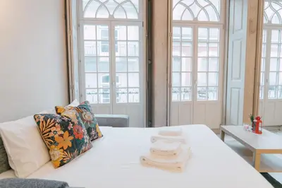 a room with a white bed and two windows at Casa Burguesa Rua do Almada - Porto city center in Porto