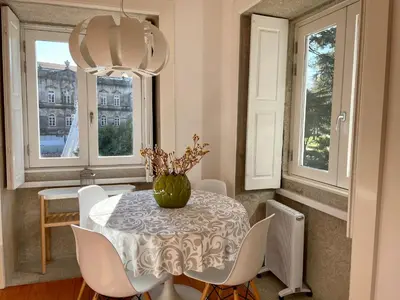 a dining room with a table and chairs and windows at Santo António Charming Flat in Porto
