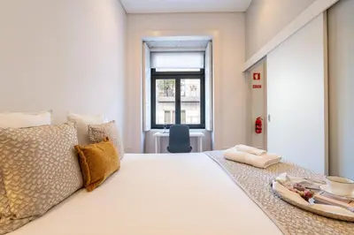 a bedroom with a white bed with a plate of food on it at Host Wise - Modern Stuning Flat w Prime Location in Porto