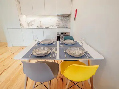 a dining room table with yellow chairs and white cabinets at OPORTO GUEST Poveiros Home in Porto