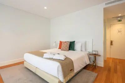 a bedroom with a large white bed with towels on it at Porto River Infante in Porto