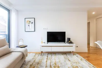 a living room with a tv on a white wall at City Center 2BR Flat w/ AC by LovelyStay in Porto