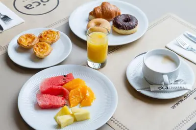 a table with plates of fruit and a glass of orange juice at Oca Vitoria Village in Porto
