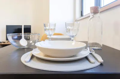 a table with a bowl and two wine glasses on it at Homely Studio w/ AC near Marquês by LovelyStay in Porto
