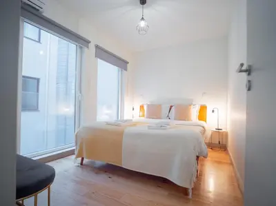 a white bedroom with a bed and a large window at Oporto City View- Trindade Lovely in Porto