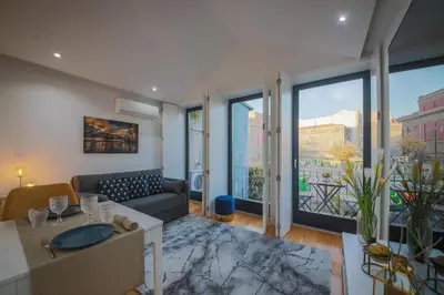 a living room with a couch and large windows at Sunshine Apartment in Porto