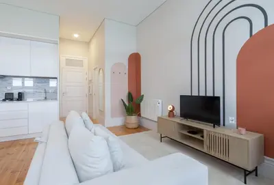 a white living room with a white couch and a tv at Habitatio - Aliados by LuxiStay in Porto