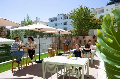 a group of people sitting at tables with umbrellas at Casual Raízes Porto in Porto