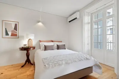 a white bedroom with a bed and a window at InBloom Apartments in Porto