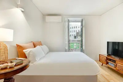 a white bedroom with a bed and a television at InBloom Apartments in Porto