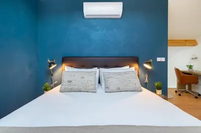 a bedroom with a white bed with a blue wall at WHome Riverside View Premium Apartment w/ AC & Terrace in Porto
