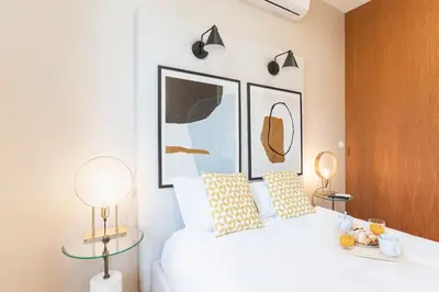 a bedroom with a white bed with two lamps at Cute & Bright Flat w/ AC by LovelyStay in Porto