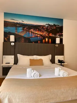 a bedroom with a large bed with a painting on the wall at Hotel Porto Interface Trindade By Kavia in Porto