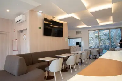 a waiting room with tables and chairs and a couch at Hotel Porto Interface Trindade By Kavia in Porto