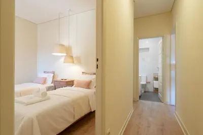 a white bedroom with two beds and a bathroom at Gaya Avenue Flats - Elegant Contemporary Flats with Balcony in Vila Nova de Gaia