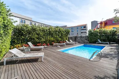 a swimming pool with chaise lounges and chairs next to a building at HM - Porto Blue Pool Apartment in Porto