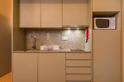 a small kitchen with white cabinets and a microwave at BRA com Apartments Oporto House 68 in Porto