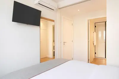 a bedroom with a bed and a flat screen tv on the wall at Catarina Serviced Apartments by HostWise in Porto