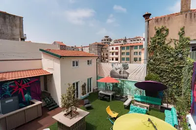 an apartment balcony with a yard with chairs and umbrellas at Rosalma Hostel in Porto