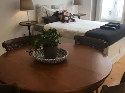 a room with a wooden table with a bed and a table with a plant at Dom Luis apartment in Porto