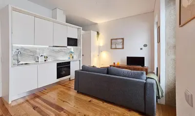a living room with a couch and a kitchen at Flores'Old Town - Elegant studio with roomy patio in Porto