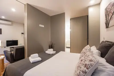 a bedroom with a bed and a chair and a television at Downtown Studio w/ AC & Patio by LovelyStay in Porto
