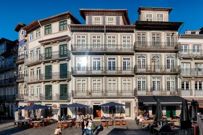 a large building with tables and umbrellas in front of it at InBloom Apartments 3 in Porto