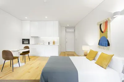 a white bedroom with a large bed and a kitchen at InBloom Apartments 3 in Porto