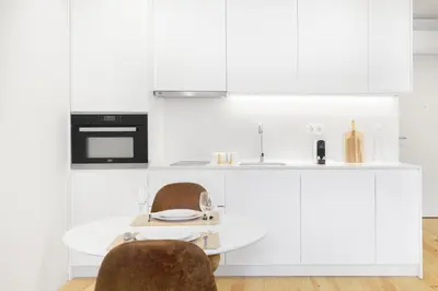 a kitchen with white cabinets and a table and chairs at InBloom Apartments 3 in Porto