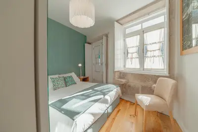 a bedroom with a bed and a chair and a window at River Eyes Apartments in Porto