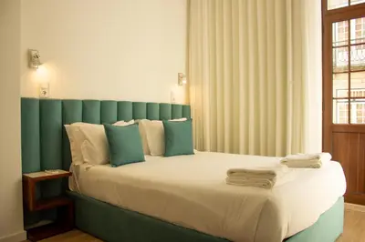 a bedroom with a large bed with a green headboard at ORM- Flores Apartment in Porto