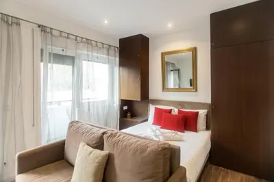 a bedroom with a bed and a couch and a mirror at Almada Studios & Suites in Porto