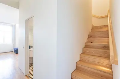 a staircase in a house with white walls and wooden floors at Modern 2BR Duplex Downtown by Art District by LovelyStay in Porto