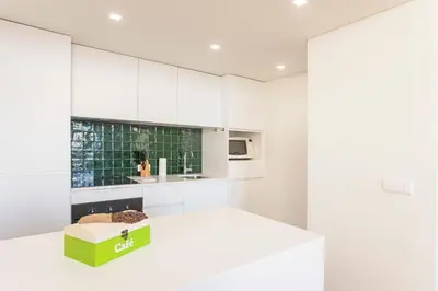 a kitchen with white cabinets and a green box on the counter at Modern 2BR Duplex Downtown by Art District by LovelyStay in Porto