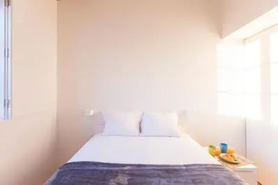 a bedroom with a bed with white walls and a window at Modern 2BR Duplex Downtown by Art District by LovelyStay in Porto