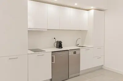 a white kitchen with white cabinets and a sink at Luxury Prime Batalha Apartments in Porto