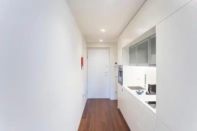a kitchen with white cabinets and a wooden floor at Bombarda Apartments by LovelyStay in Porto