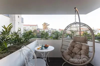 a swing chair on a balcony with a table at Bombarda Apartments by LovelyStay in Porto