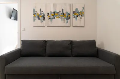 a couch in a living room with three paintings on the wall at PortoVivo Quental Terrace in Porto