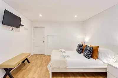 a white bedroom with a bed and a table at Bonjardim Downtown Apartments by DA'HOME in Porto