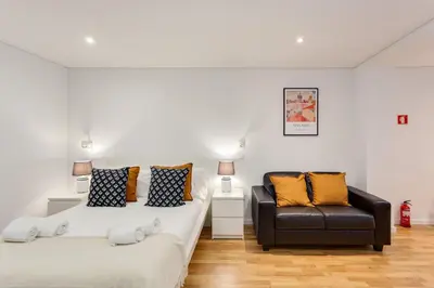 a bedroom with two beds and a leather couch at Bonjardim Downtown Apartments by DA'HOME in Porto