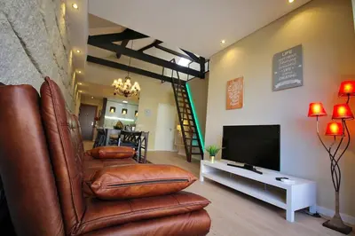 a living room with a leather chair and a television at HEART OF THE CITY 7 ! in Vila Nova de Gaia