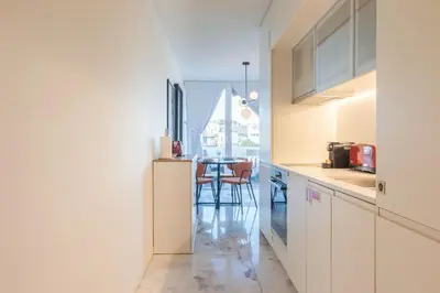 a kitchen with white cabinets and a table with chairs at Liiiving in Porto - Luxury Gallery Apartment II in Porto