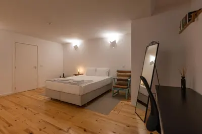 a bedroom with a bed and a mirror and a chair at ORM Torrinha Apartment in Porto