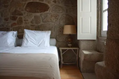 a bedroom with a bed and a stone wall at Casa Dos Caldeireiros in Porto